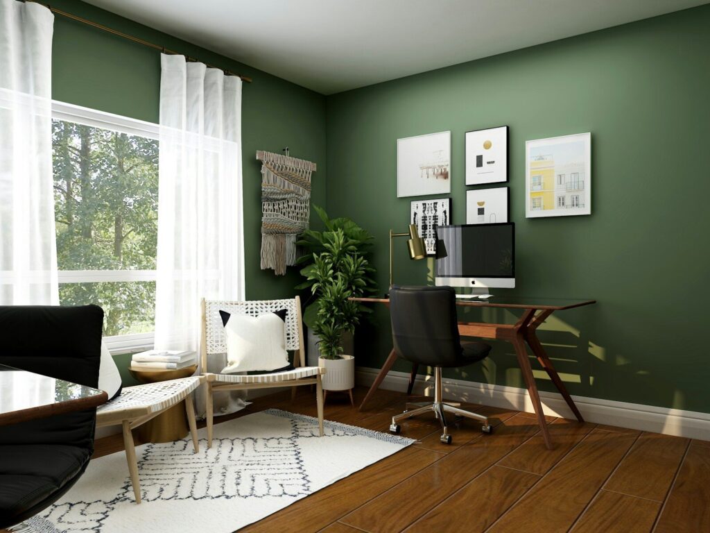 A home office with a wooden desk, black chair, and green walls in mid term rental
